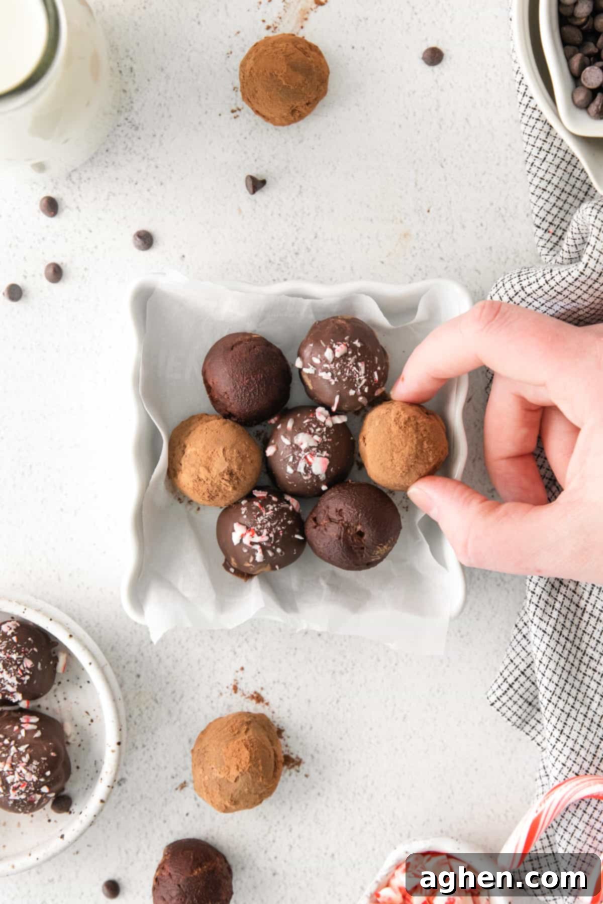 Hand reaching out to take one boozy truffle from plate of boozy peppermint schnapps truffles