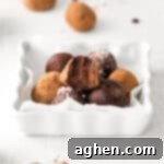 Boozy Dark Chocolate Peppermint Truffles on white plate, one truffle has a bite taken out of it to show rich and fudgey ganache center.