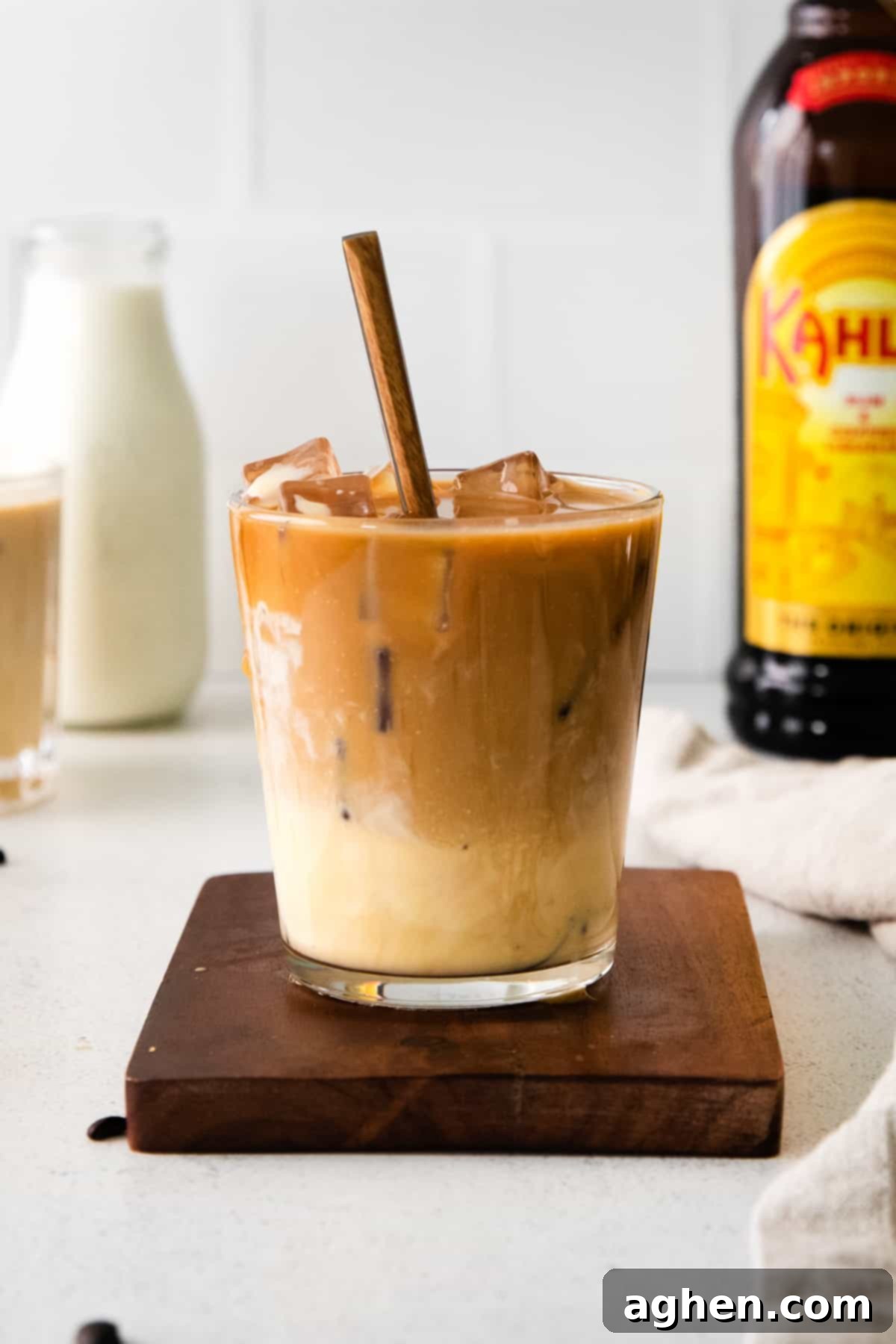 Creamy Eggnog White Russian cocktail with a spoon, surrounded by bottles of Kahlua and eggnog, ready for festive gatherings.