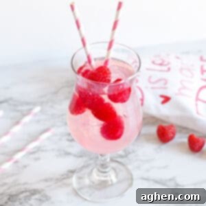 Pink Moscato Sangria with fresh raspberries in a cocktail glass with pink and white striped paper straws