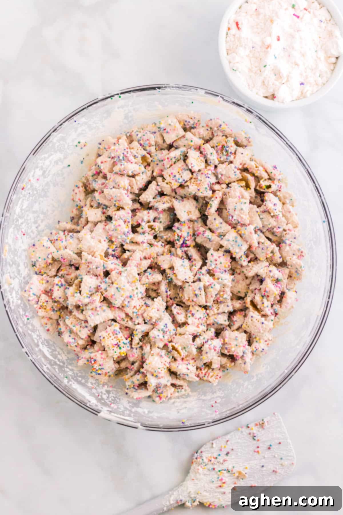 Large glass bowl with chex coated in white chocolate and sprinkles