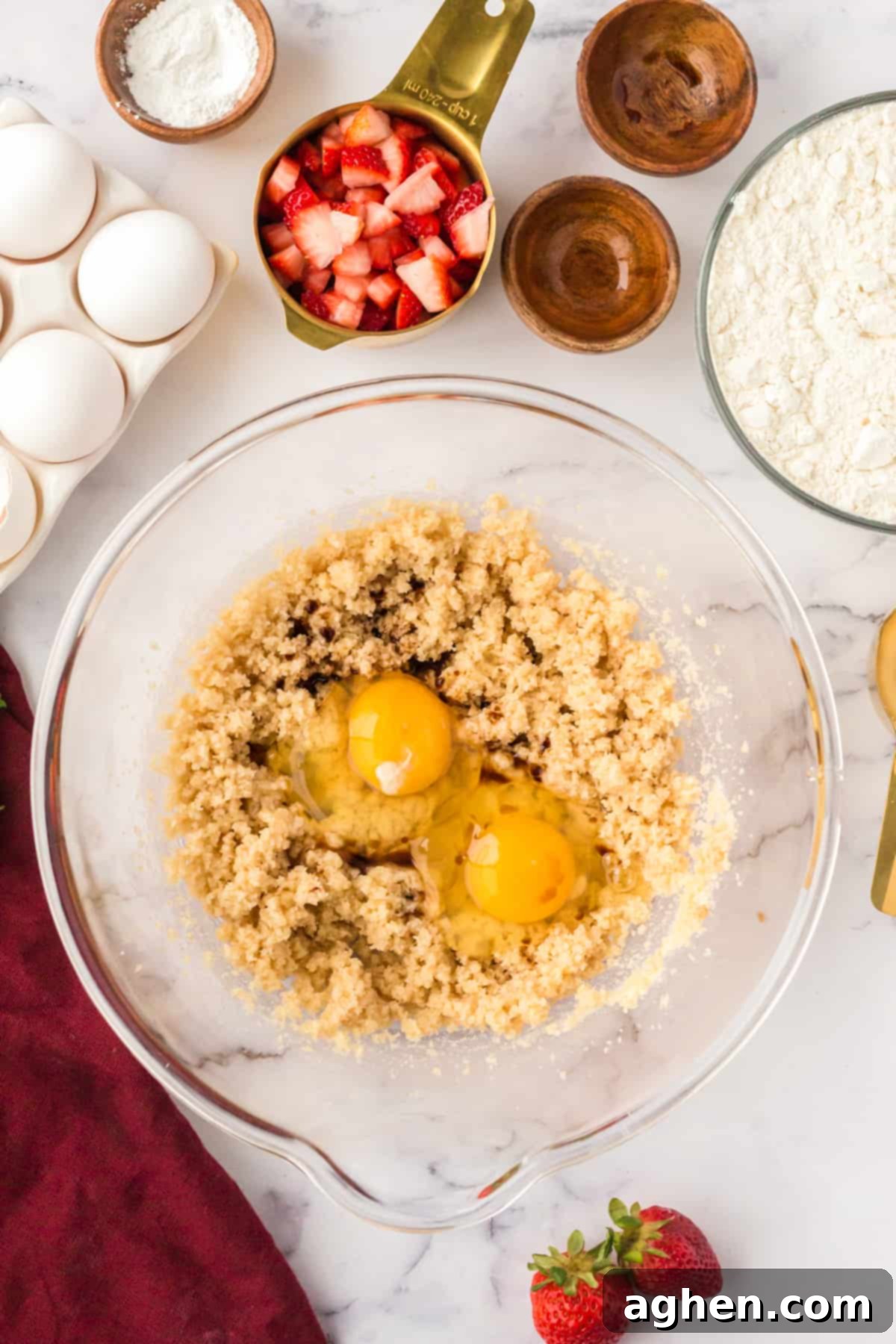 A large mixing bowl holding the creamed butter and sugar, with two whole eggs and vanilla extract freshly added, ready for mixing.