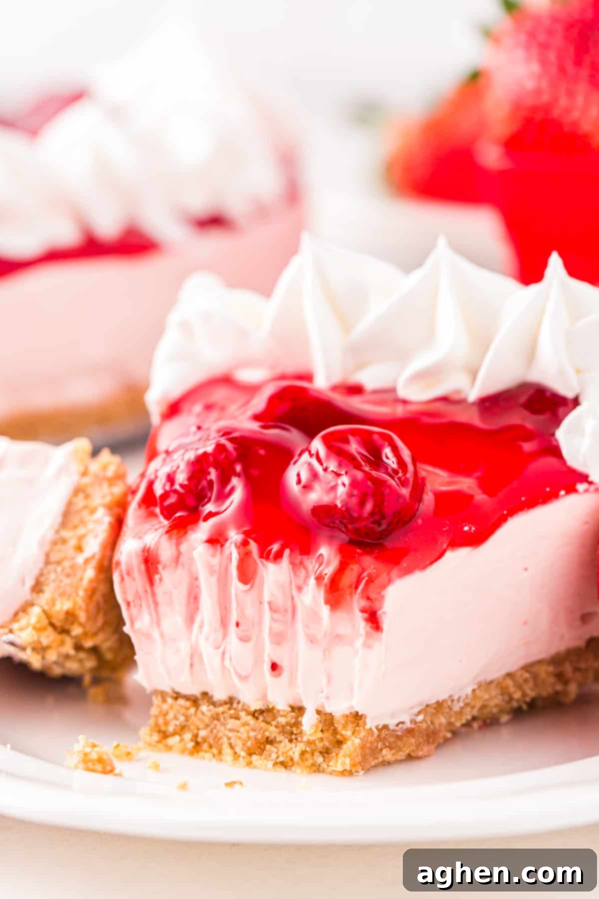 Piece of no bake strawberry cheesecake with bite taken out of it.