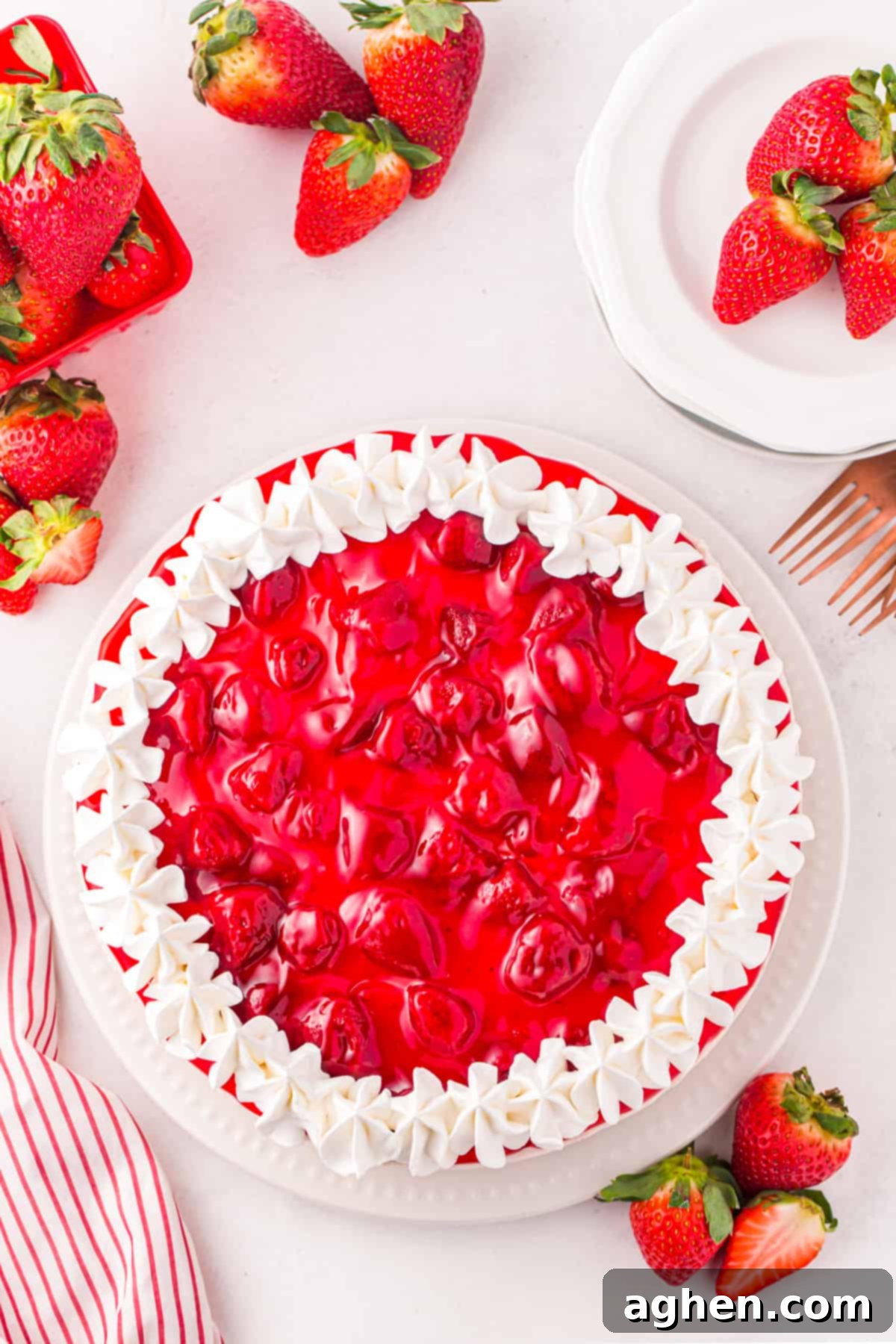 Whipped topping piped around edge of cheesecake. Strawberry pie filling is in center of cheesecake.