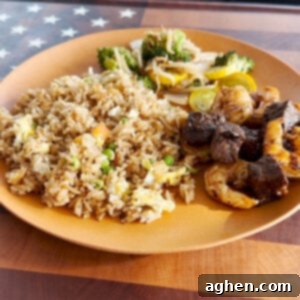 Close-up of freshly cooked fried rice with steak, shrimp, and vegetables on a serving plate.