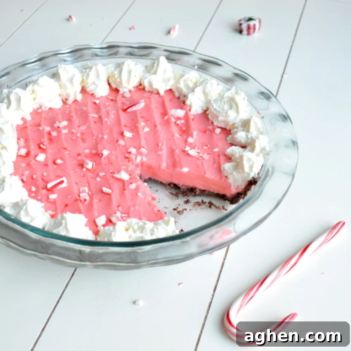 Sliced peppermint pie on a white plate, showcasing its creamy pink filling and chocolate crust, ready to be enjoyed as a holiday dessert.