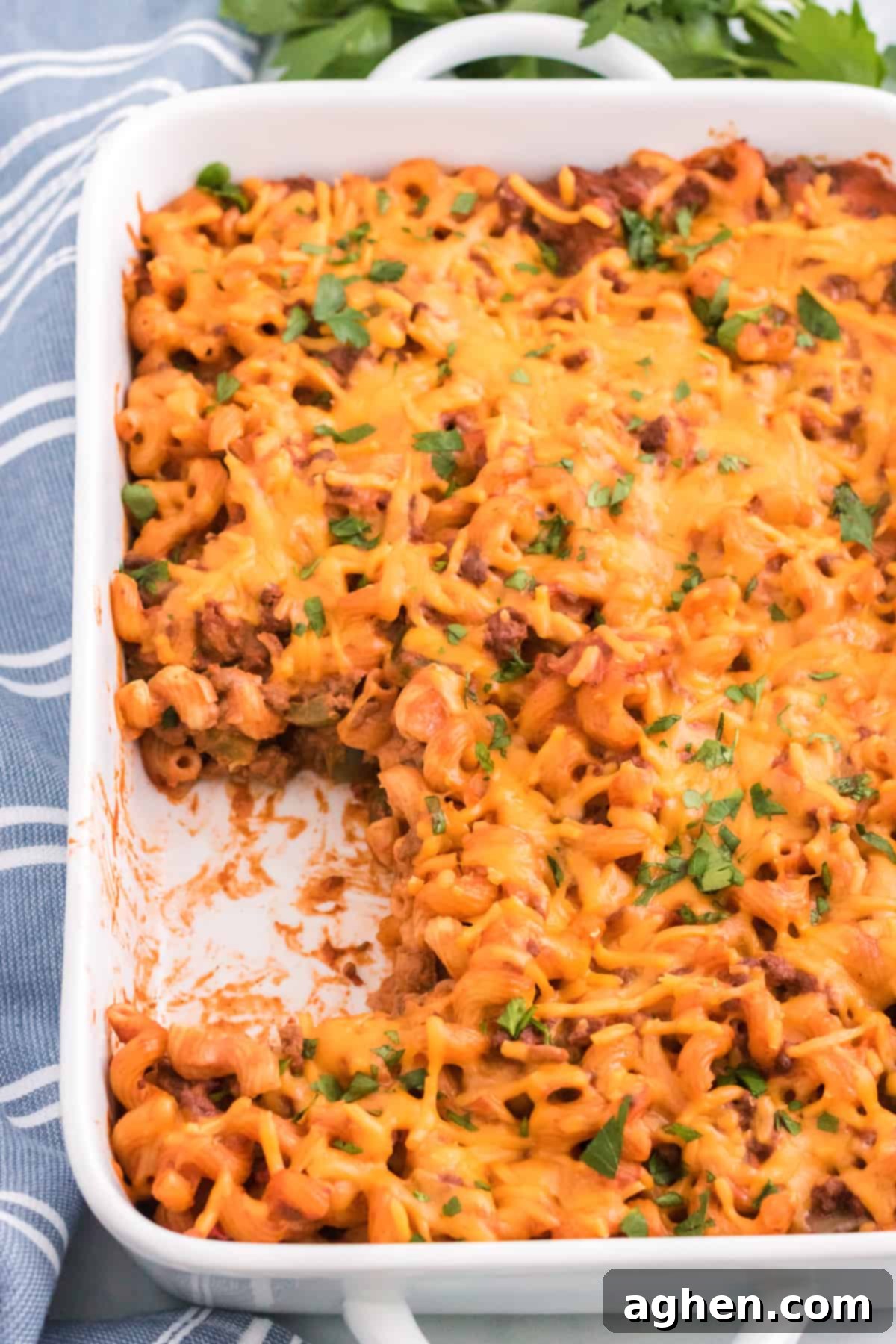 Sloppy Joe Casserole in white 9 x 13 baking dish topped with melted cheese and fresh parsley, ready to be served.