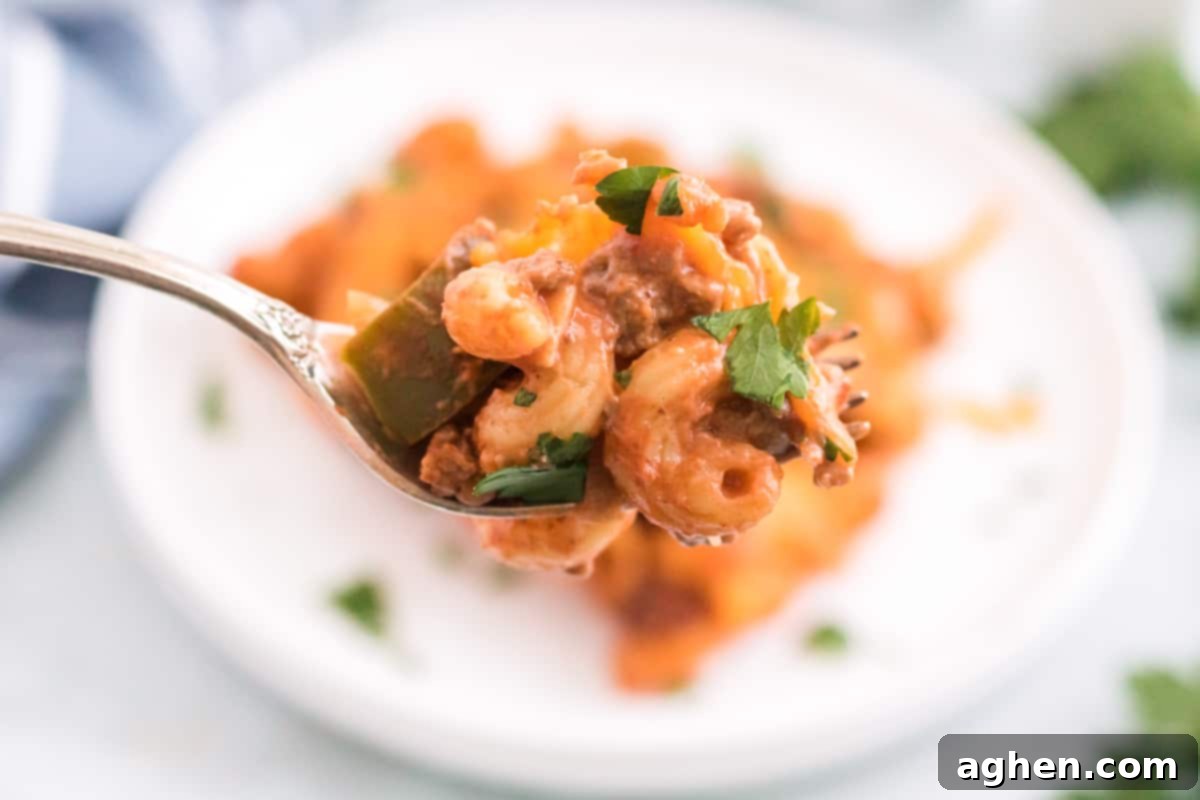 A forkful of ground beef Manwich and pasta bake, showing the cheesy, saucy texture.