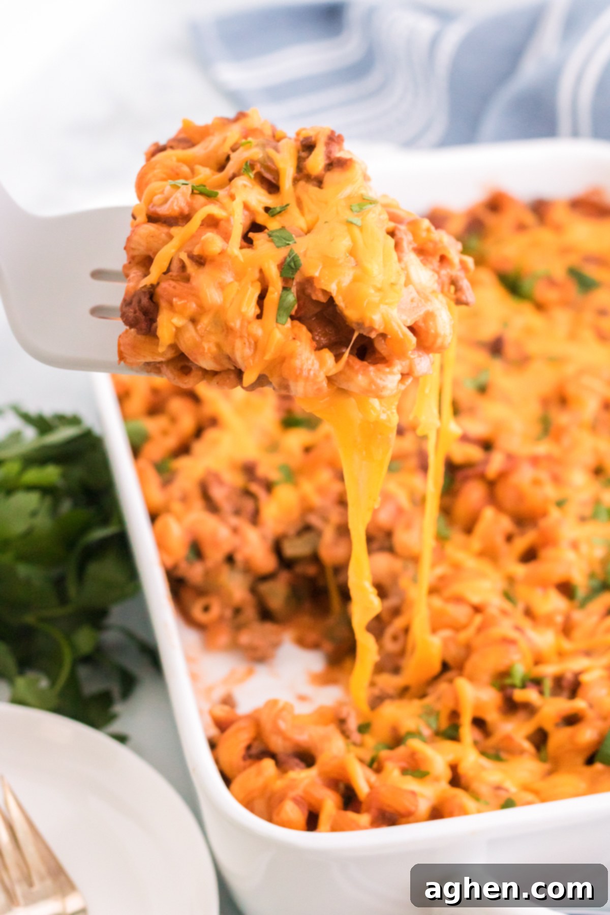 A serving of Cheesy Sloppy Joe Casserole being lifted with a spatula from a baking dish, showcasing the melty cheese and pasta.