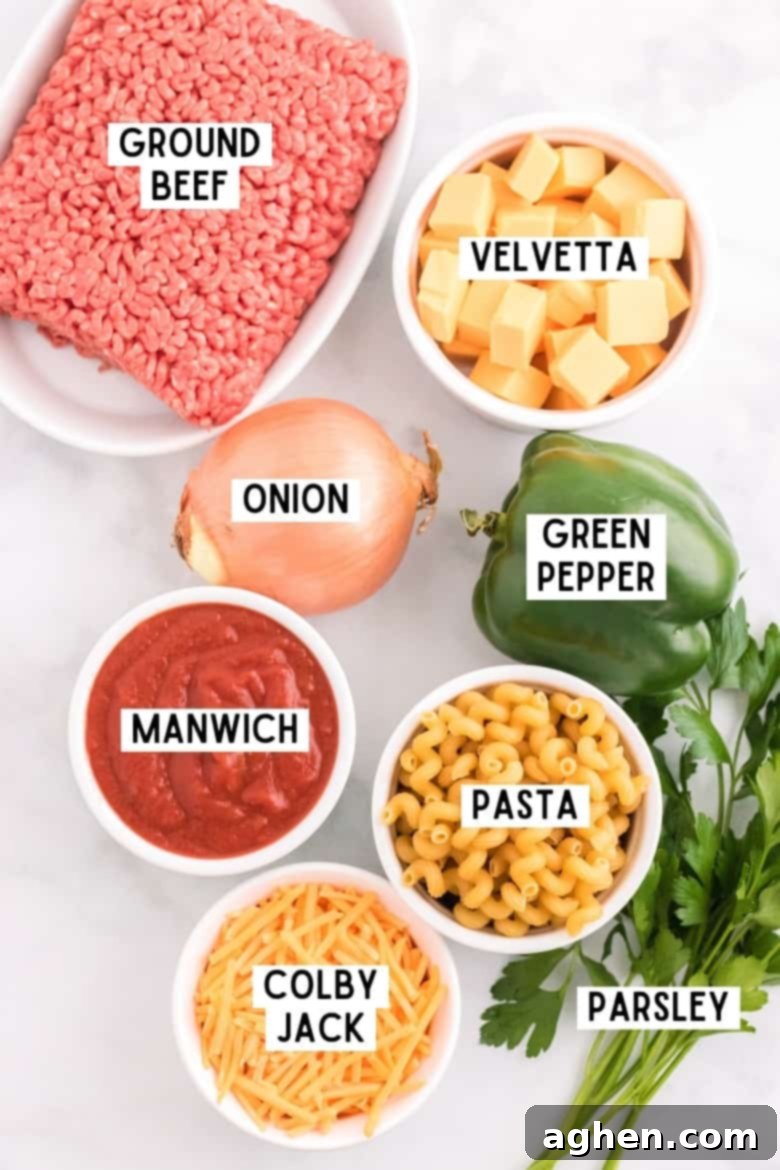 Individual ingredients for Sloppy Joe Casserole: ground beef, cubed Velveeta, chopped onion, green bell pepper, uncooked pasta, Manwich sauce, fresh parsley, and shredded Colby Jack cheese.