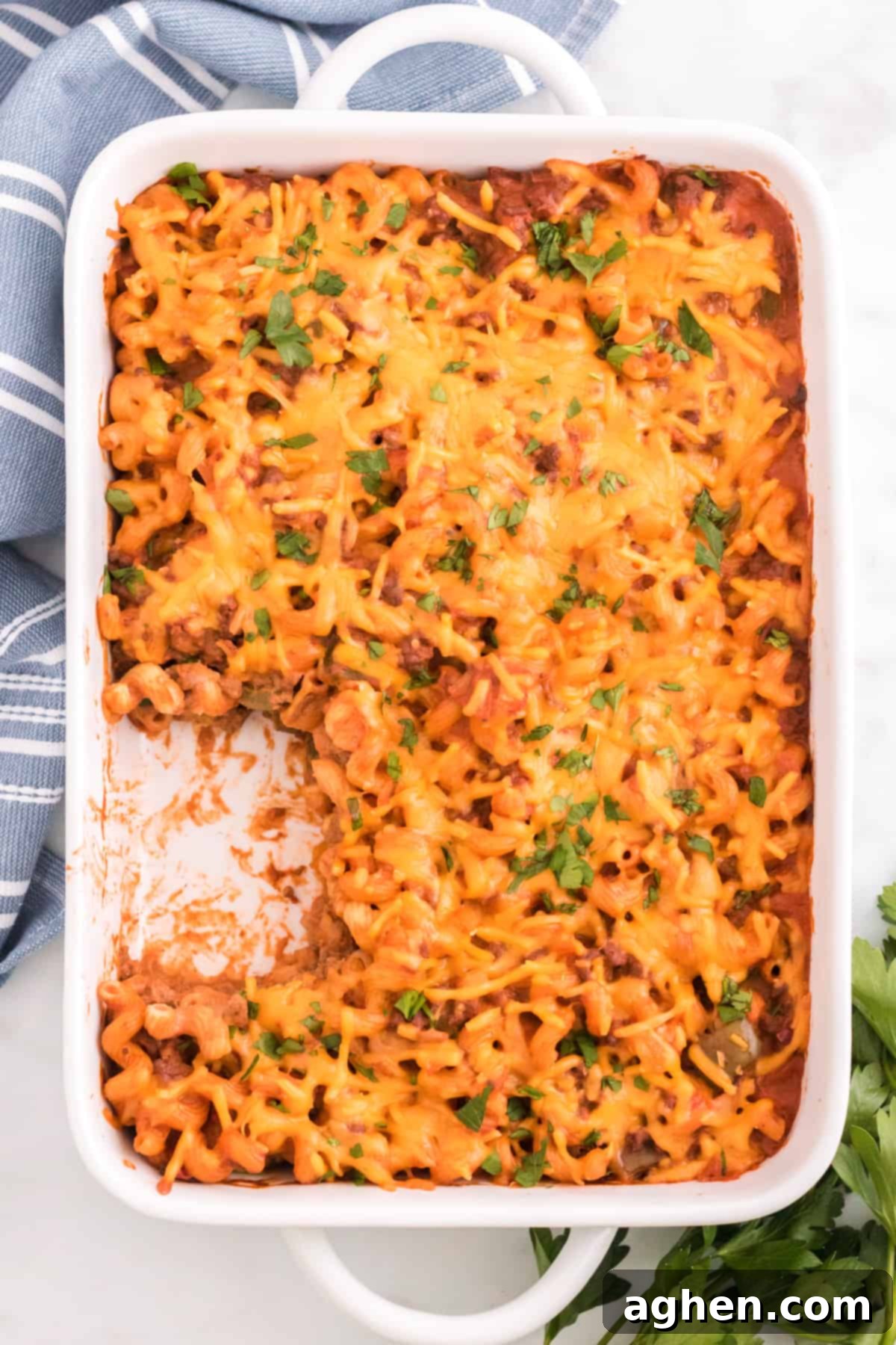 Baked Manwich casserole with pasta and melted cheese in a 9 x 13 pan, with a single serving removed.