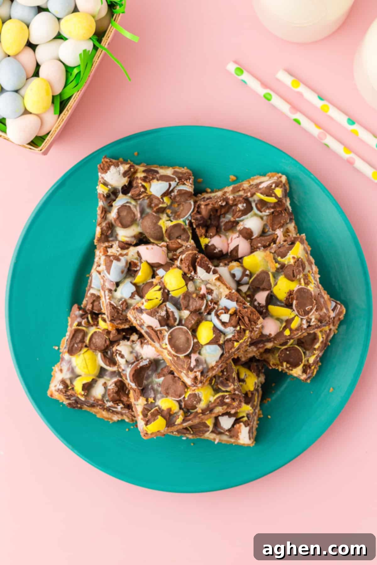 Magical Easter Cookie Bars 11 Top-down photo of mini egg cookie bars just into squares and laid on teal plate. Mini chocolate eggs, paper straws, and glasses of milk are in background.