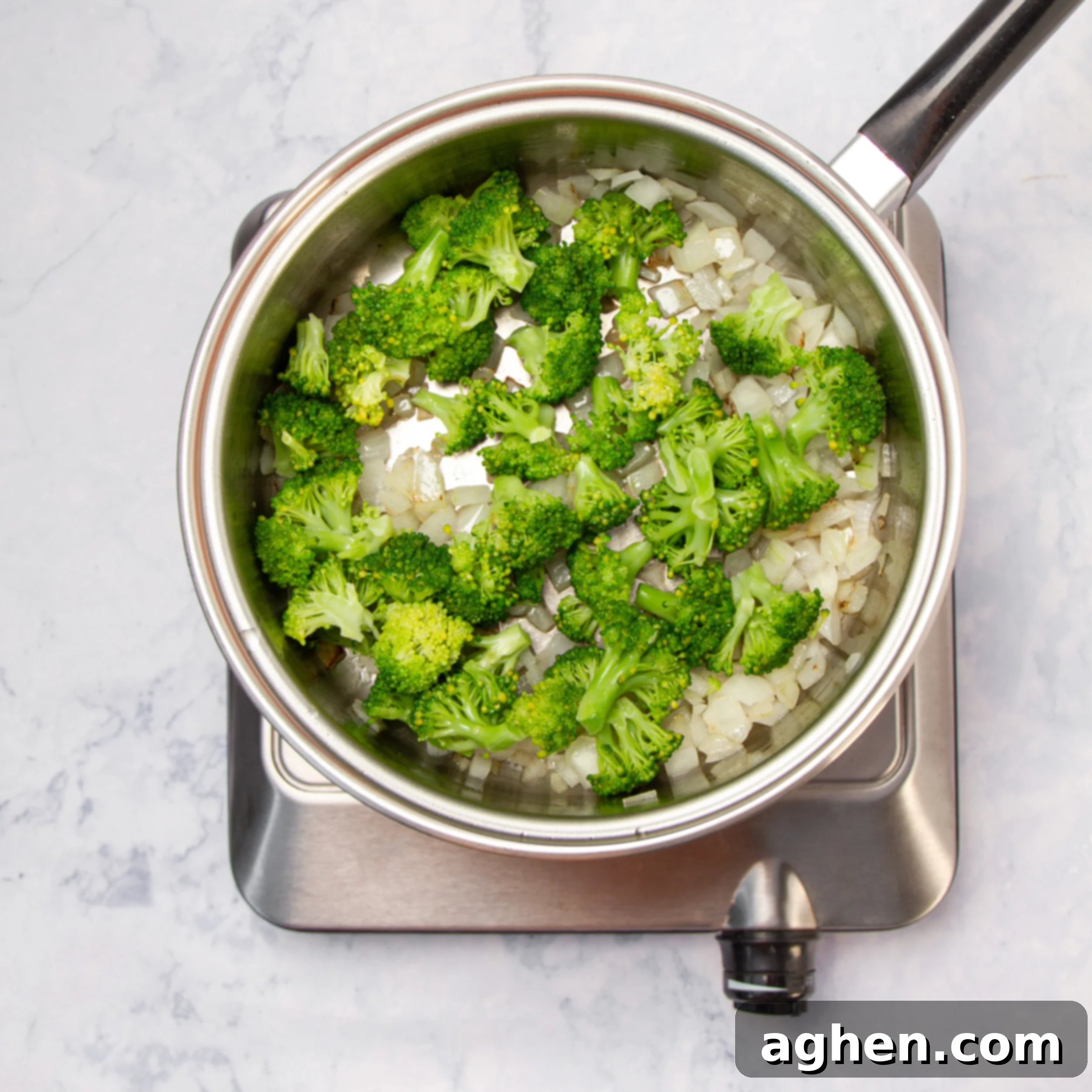 Cheesy Broccoli Breakfast Casserole 4 Onions and broccoli sautéing in a small pot.