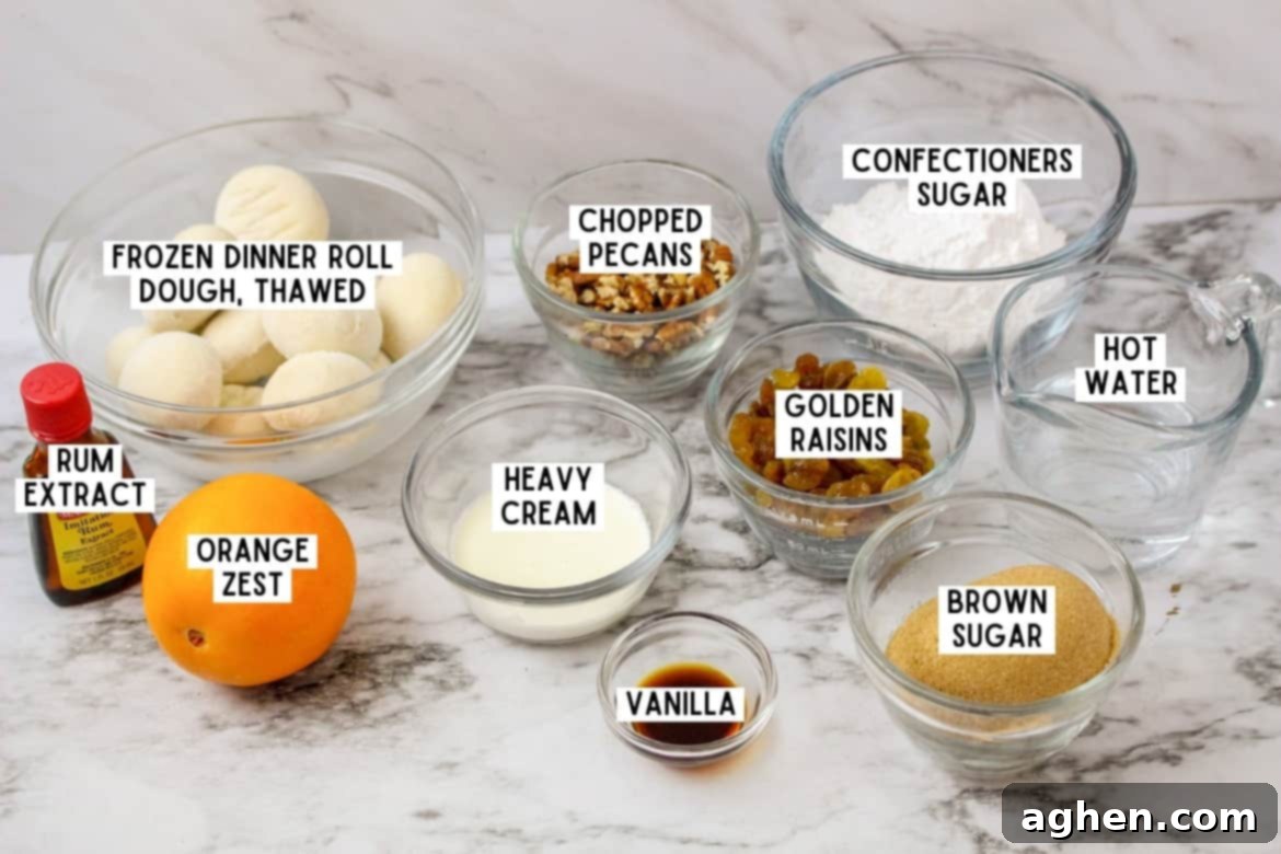 Bottle of imitation rum extract, one orange, and the following ingredients in bowls: rhodes frozen dinner rolls, chopped pecans, confectioners sugar, golden raisins, brown sugar, vanilla, heavy cream, vanilla, and hot water