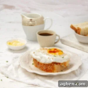 Air Fryer Fried Eggs: Golden, Crispy Perfection 7 Perfectly cooked air fryer egg on top of a piece of thick-cut toast, on a plate with a cup of coffee behind it.