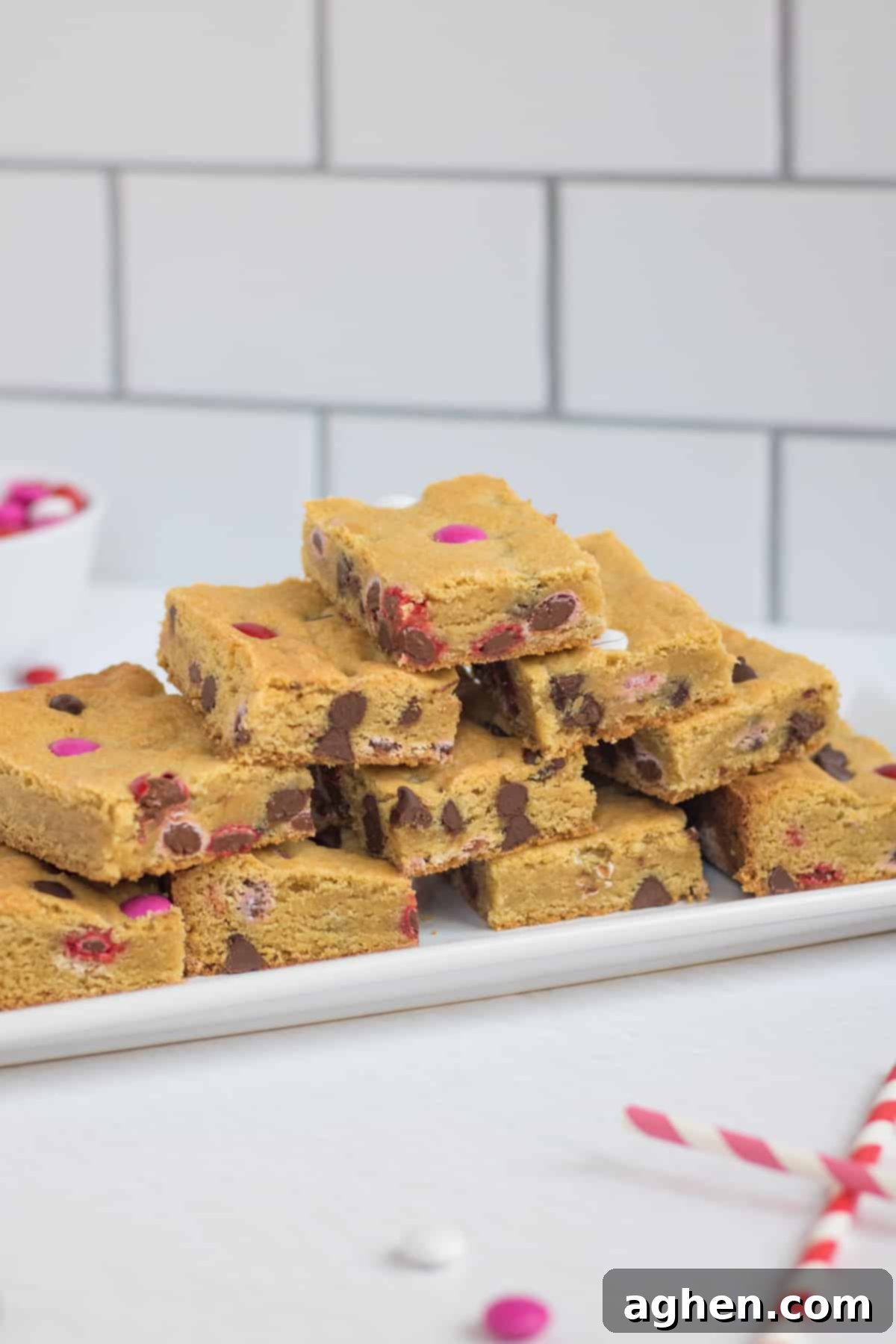 Sweetheart Cookie Squares 3 Stacked Valentine's Day Cookie Bars featuring festive chocolate chips and M&M candies, arranged beautifully on a white platter.