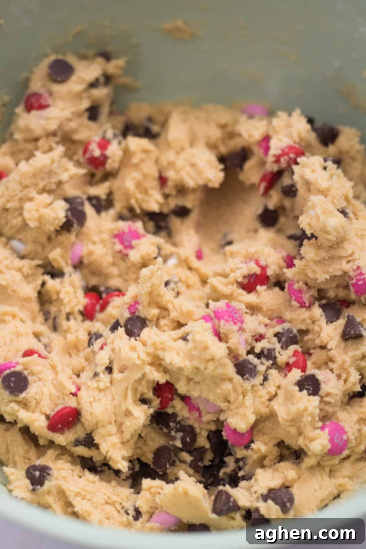 Sweetheart Cookie Squares 6 Close-up of chocolate chip cookie dough generously studded with festive pink, red, and white M&Ms, ready for baking.