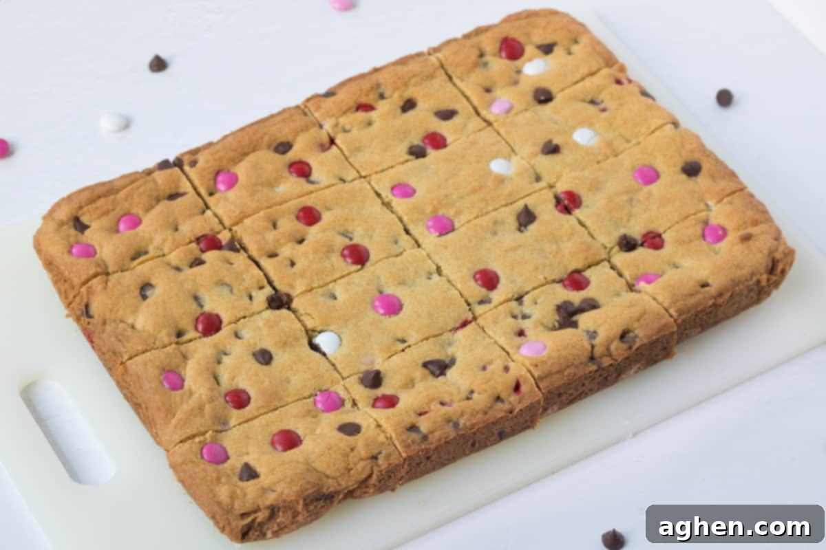 Sweetheart Cookie Squares 8 Freshly baked chocolate chip cookie bars with Valentine's M&M candies, sliced into 12 perfect bars on a wooden cutting board.