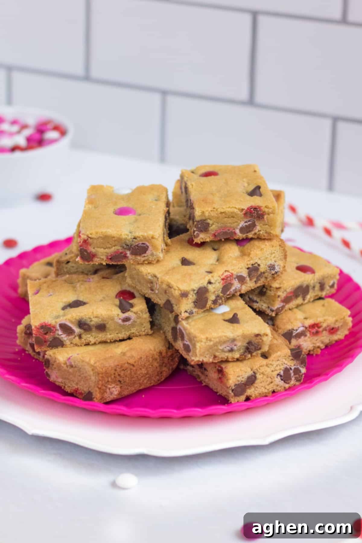 Sweetheart Cookie Squares 9 Festive Valentine's Day Cookie Bars arranged on a pink serving platter, surrounded by red and pink paper straws and colorful M&M candies, perfect for a celebration.