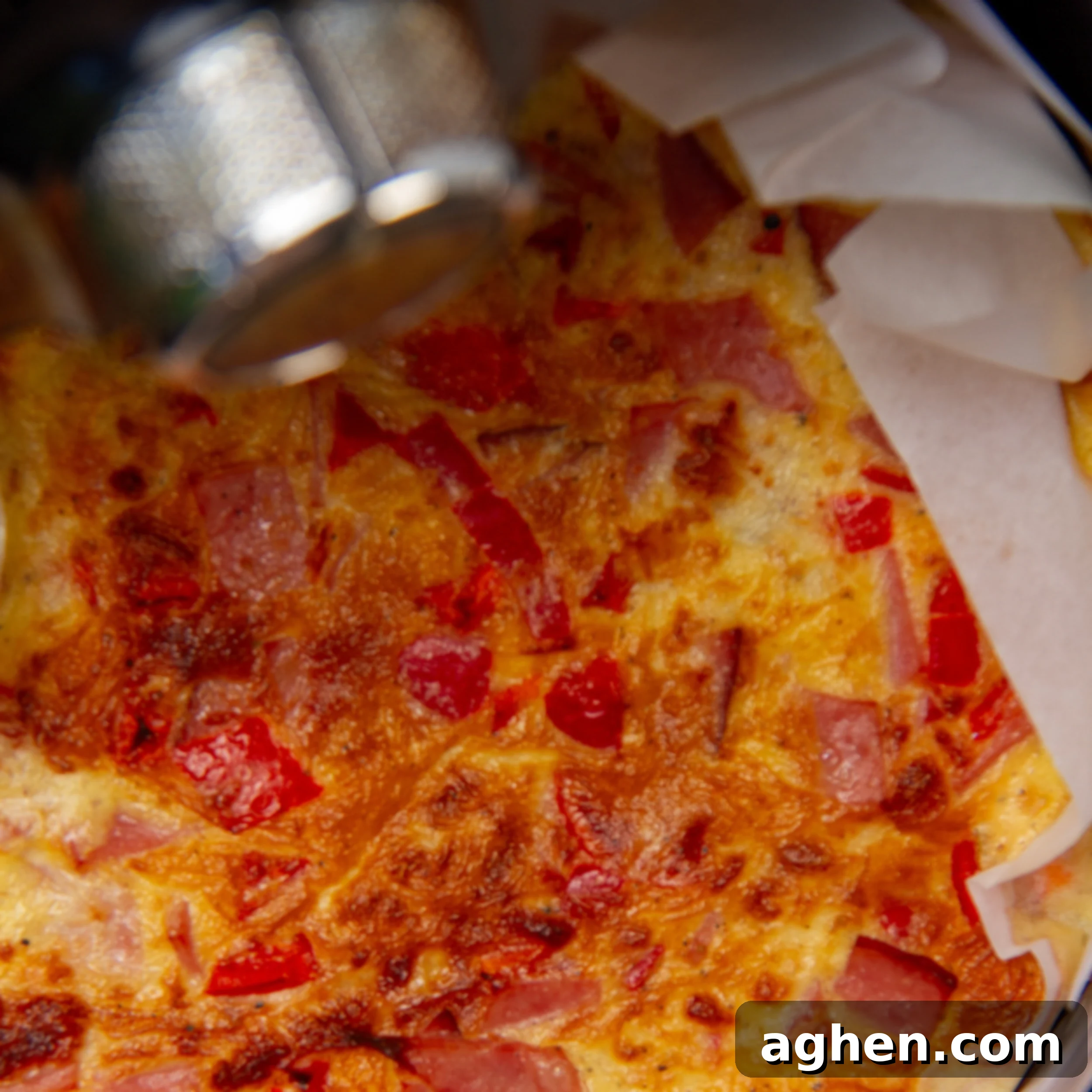 The frittata mixture cooking in a parchment-lined air fryer basket, showing the edges just starting to brown.