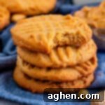 Old-fashioned peanut butter cookies with criss cross pattern on the top and bite taken out of one cookie.