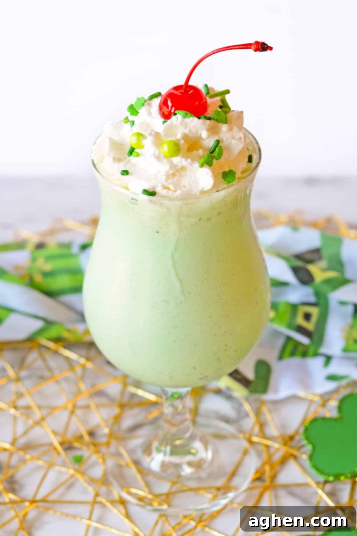 Festive Boozy Shamrock Shake, topped with whipped cream, a maraschino cherry, and green sprinkles, ready for St. Patrick's Day.