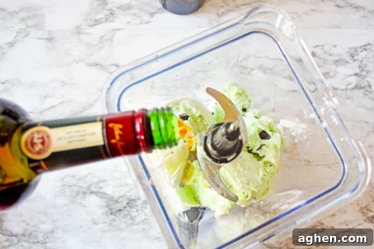 Jameson Irish Whiskey being poured into a blender with mint chocolate chip ice cream, milk, and Baileys.