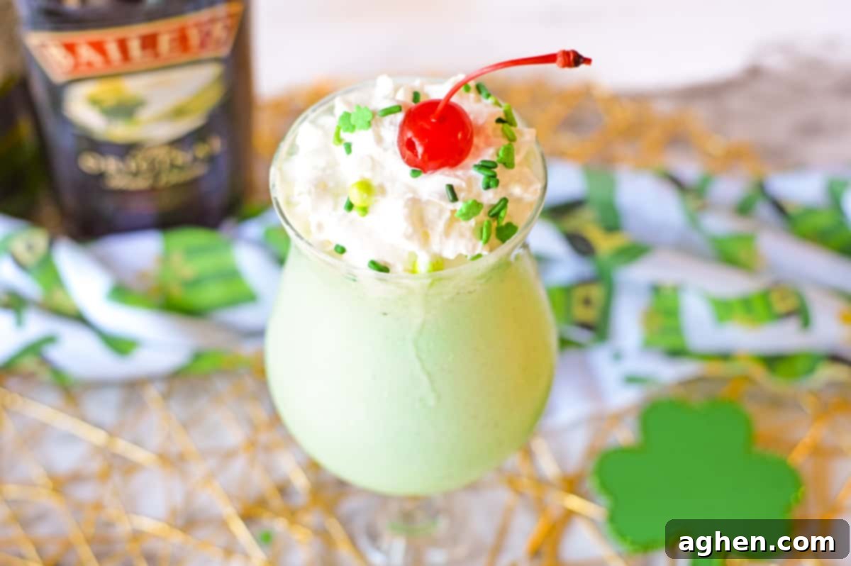Beautifully garnished Boozy Shamrock Shake featuring whipped cream, festive green sprinkles, and a maraschino cherry, ideal for St. Patrick's Day celebrations.