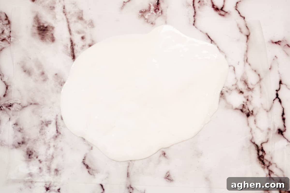 Melted white chocolate spread evenly on wax paper, ready for decoration.
