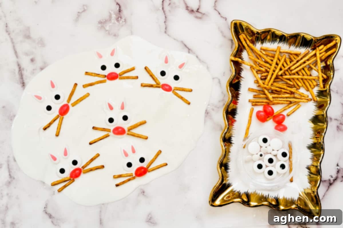 Plate with pretzel sticks, pink jelly beans, and candy eyes next to melted white candy with bunny faces being created.