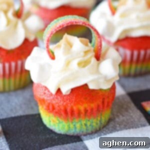 Rainbow Cupcakes with whipped cream cream cheese frosting and decorated with rainbow candy on top.