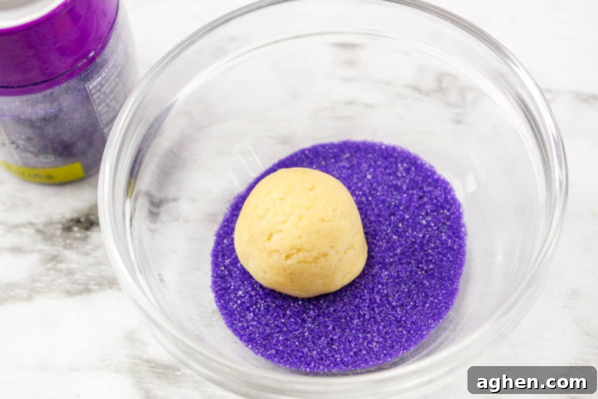 Cookie dough ball being rolled in colorful sanding sugar for Easter Blossom Cookies.