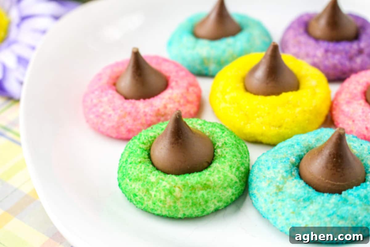 Sugar cookies rolled in colorful sugar with creamy chocolate kisses pressed in the center, arranged beautifully.
