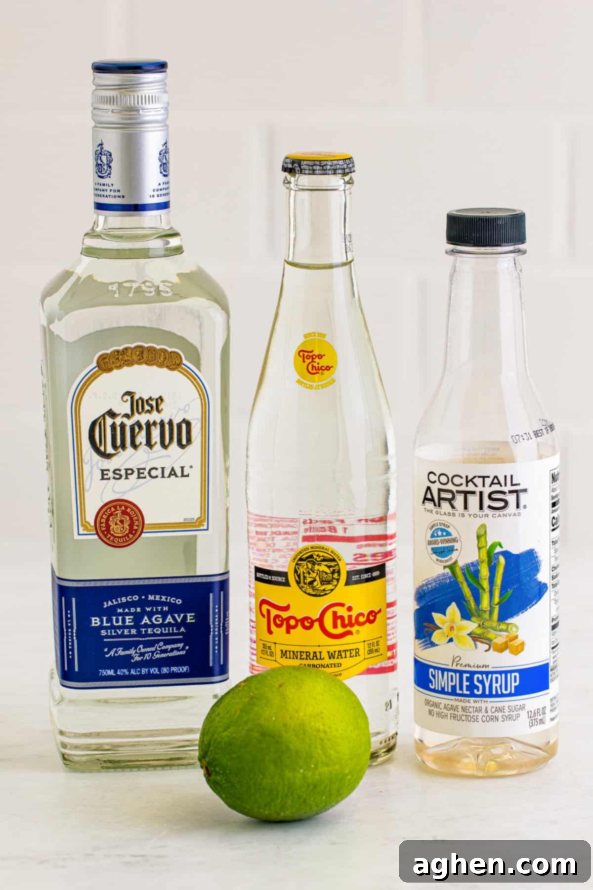 Ingredients for Ranch Water Cocktail: Tequila blanco, Topo Chico mineral water, simple syrup, and fresh limes, neatly arranged.
