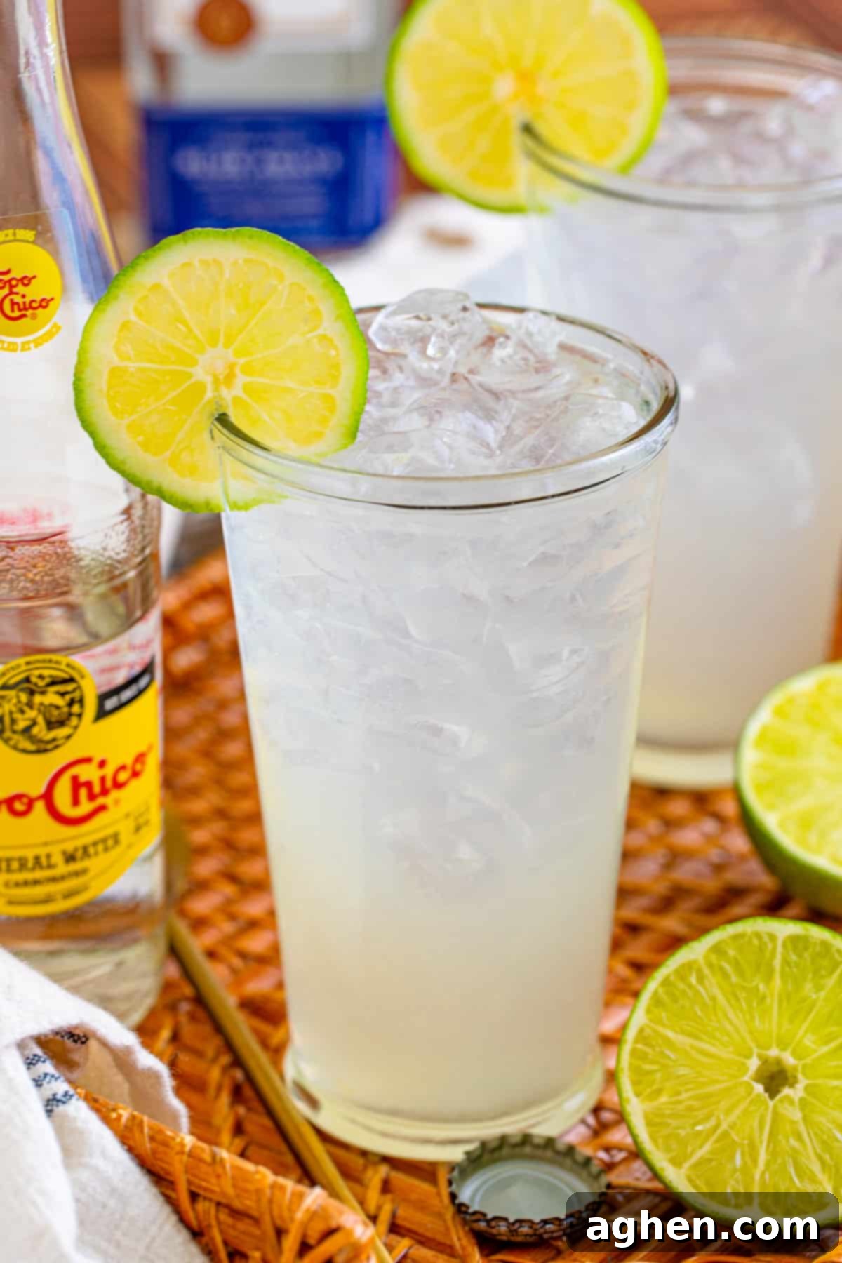 Ranch water drink with tequila, fresh lime, and Topo Chico on a rustic straw tray, ready to be served.