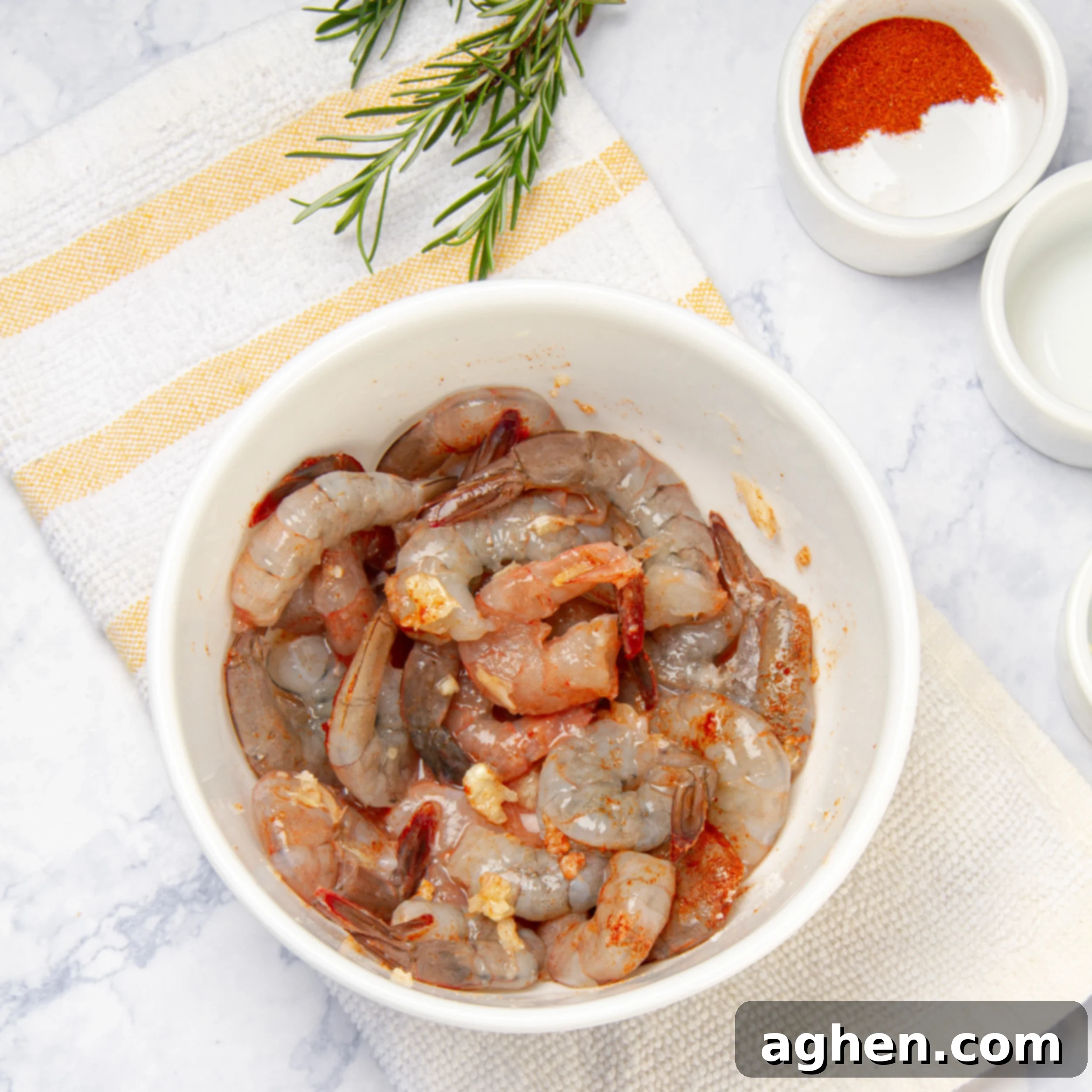 Shrimp marinating in a small bowl with lemon juice, paprika, and salt.