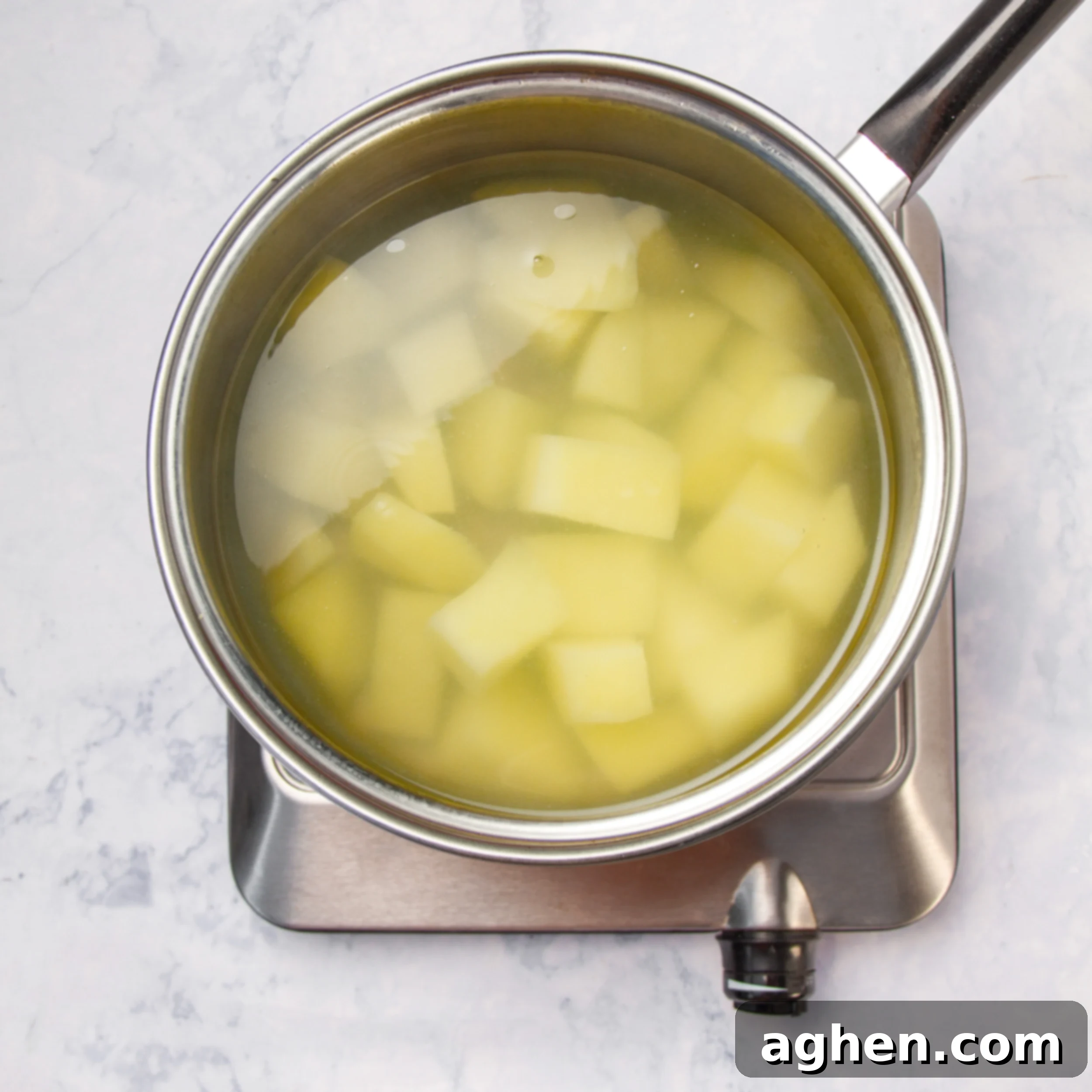 A large potato cooking in a pot of boiling water.