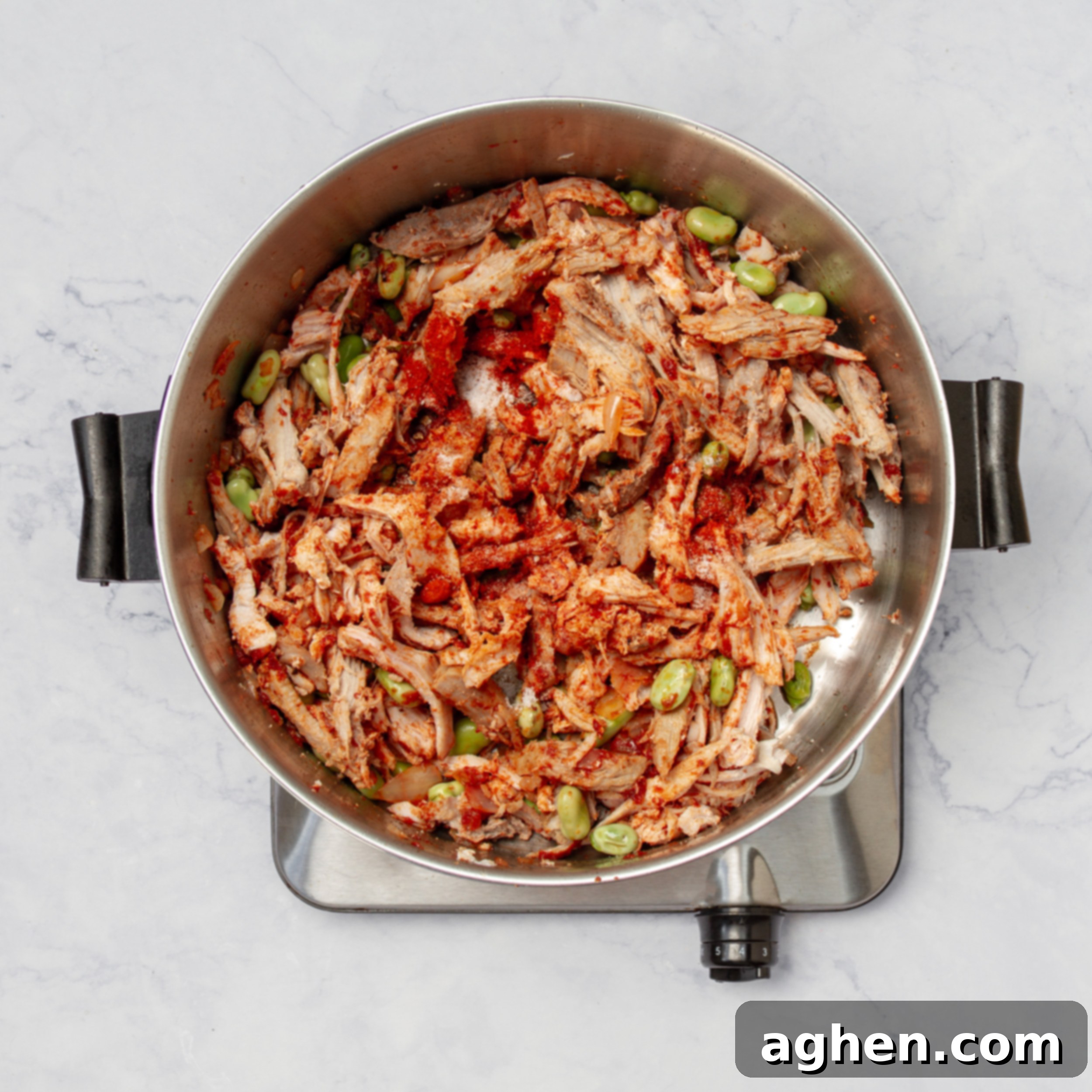 Brunswick Stew: Delicious and Weight Watchers Approved 5 Cooked shredded chicken and pulled pork being added to the sautéed aromatics and tomato paste in the pot, ready to be spiced.