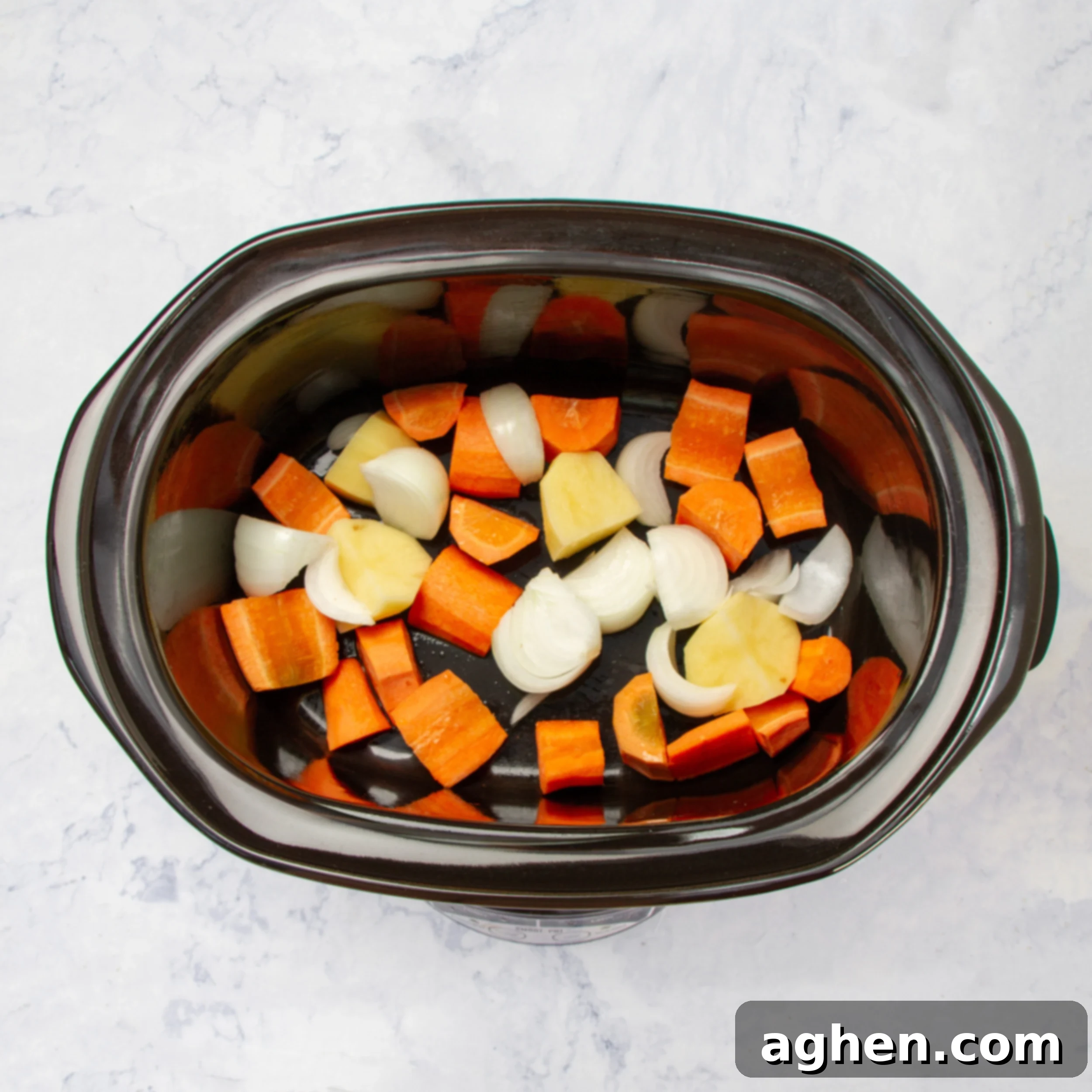 Chunks of carrots, potatoes, and onions added to the slow cooker before chicken.