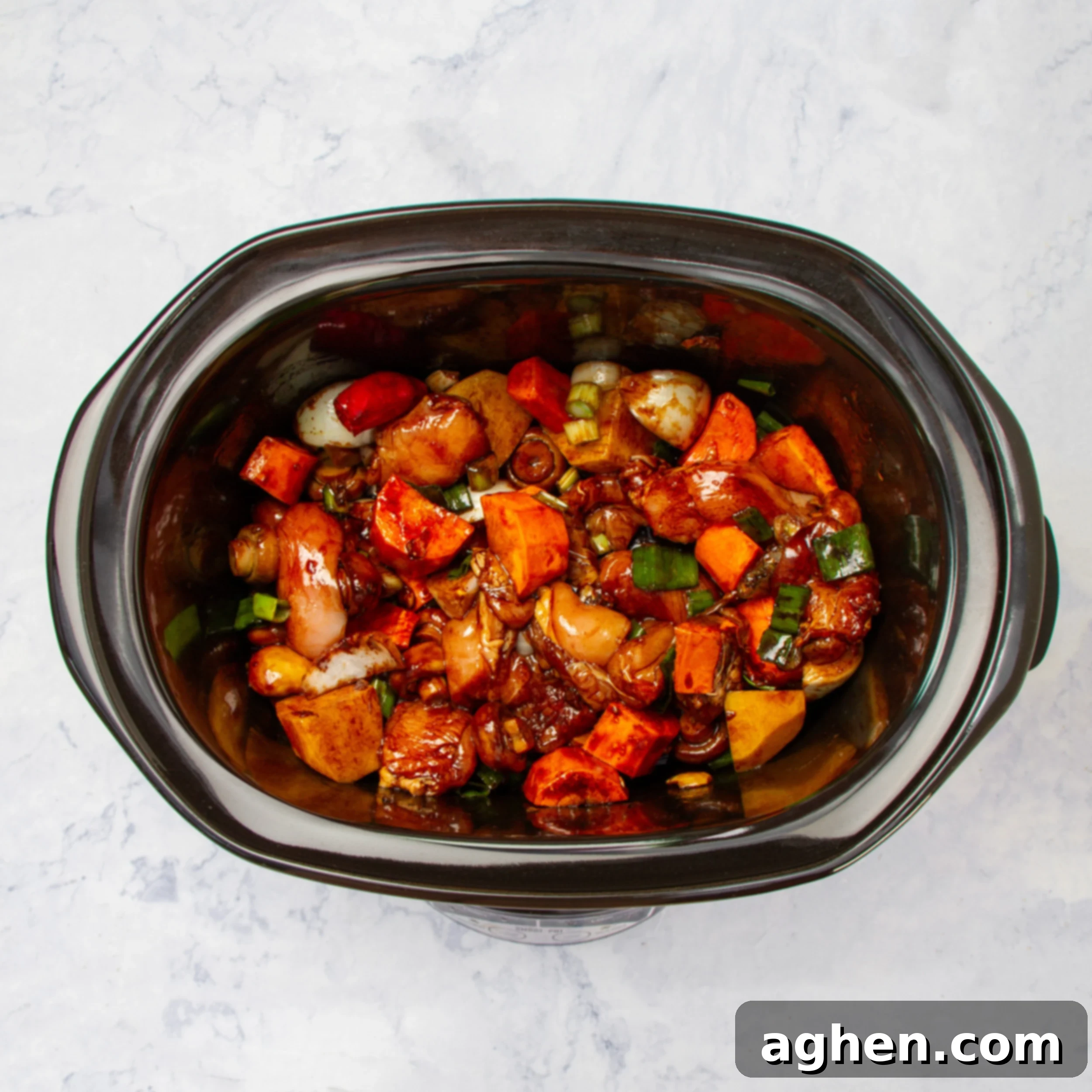 Sauce being poured over the chicken and vegetables in the slow cooker, ready for cooking.