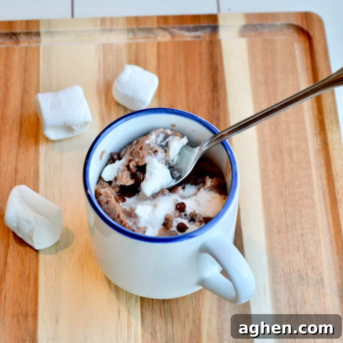 A perfectly cooked chocolate mug cake, topped with fluffy marshmallows, in a ceramic mug.
