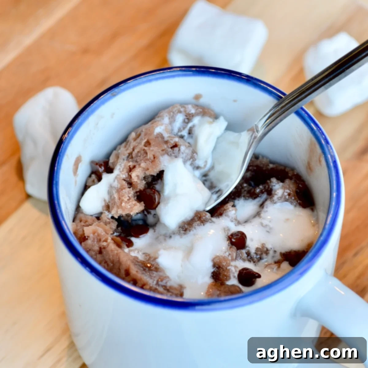 An up-close image of the finished hot cocoa mug cake, still in its mug, with melted marshmallows on top.