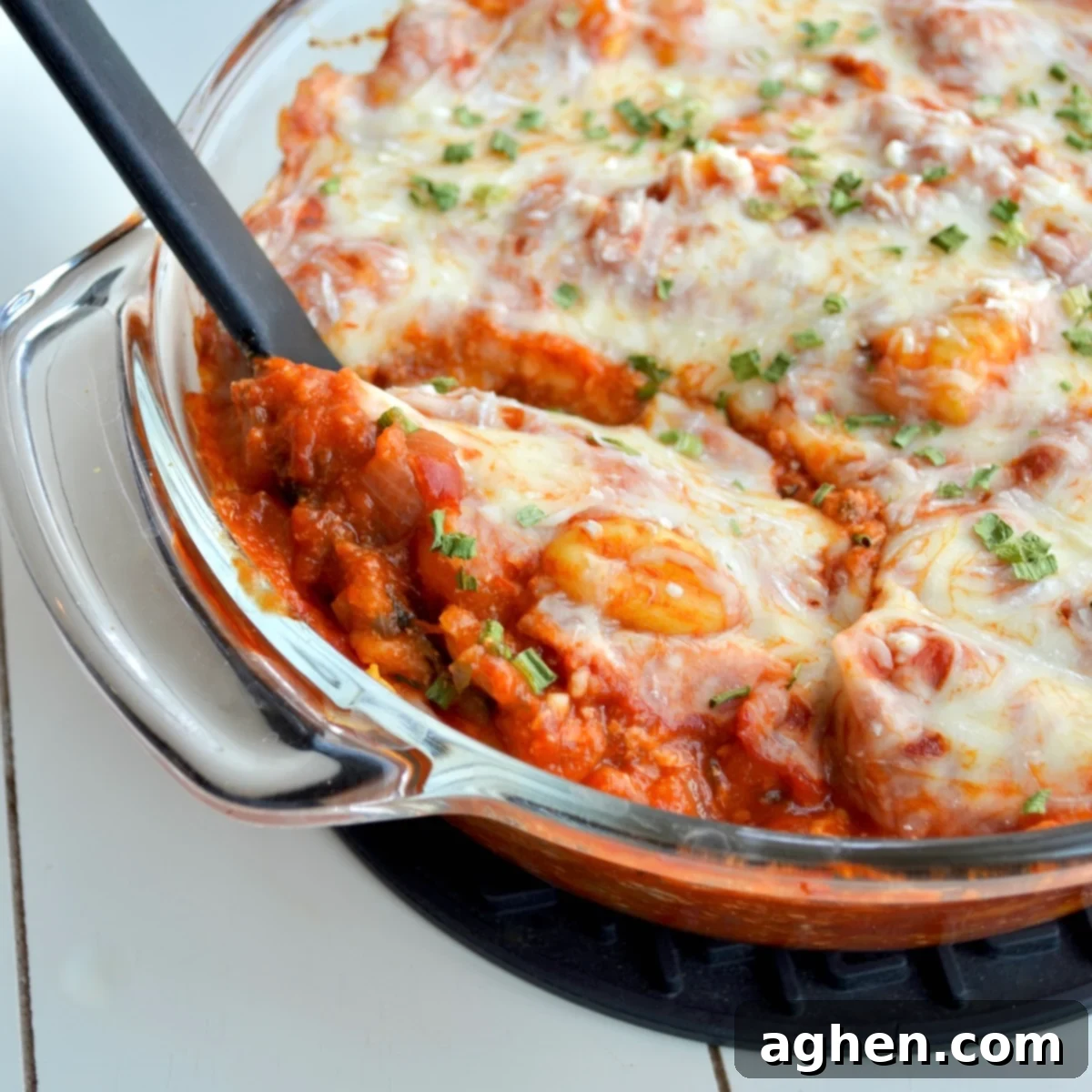 A close-up shot of a baked Weight Watchers Cheesy Gnocchi Casserole, showcasing the golden-brown melted mozzarella cheese and rich marinara sauce with visible potato gnocchi, bell peppers, and onions.
