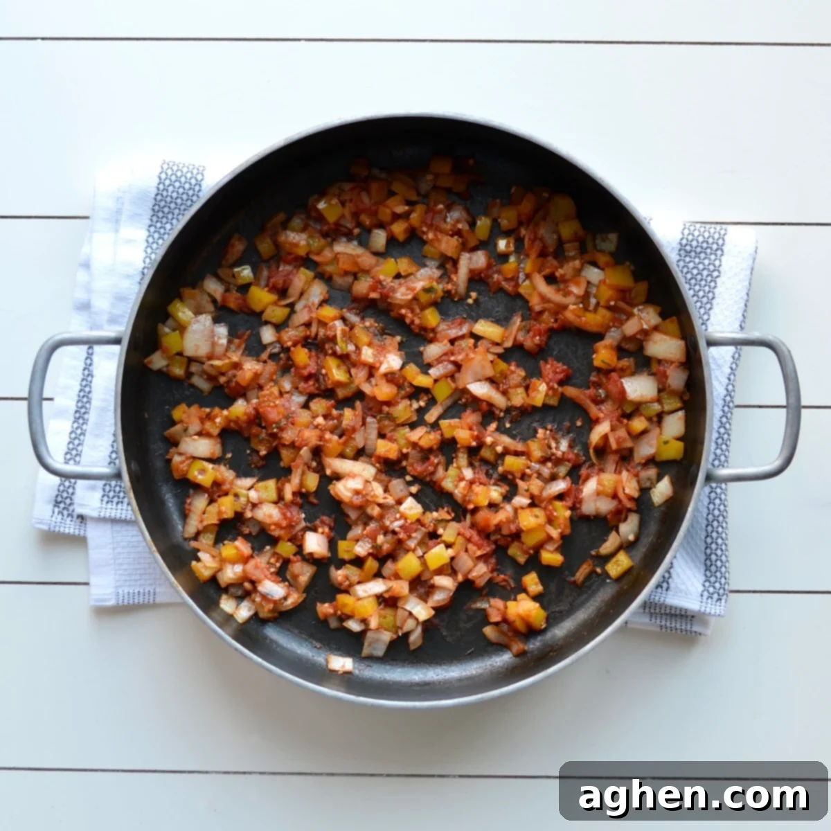 Close-up of chopped bell peppers and onions sautéing in a pan with crushed tomatoes, steam rising, illustrating the initial cooking steps for the gnocchi casserole.