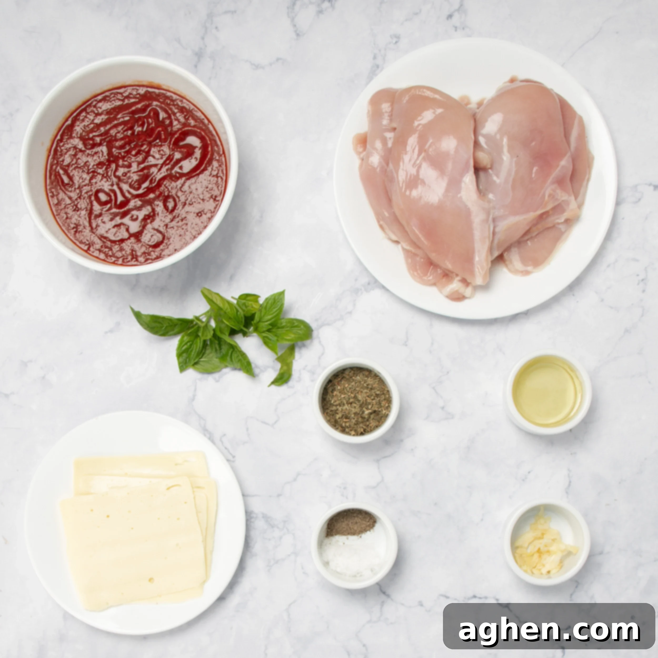 All the fresh ingredients for Pizzaiola chicken, including chicken breasts, marinara sauce, mozzarella, and basil, neatly arranged in separate dishes on a counter.