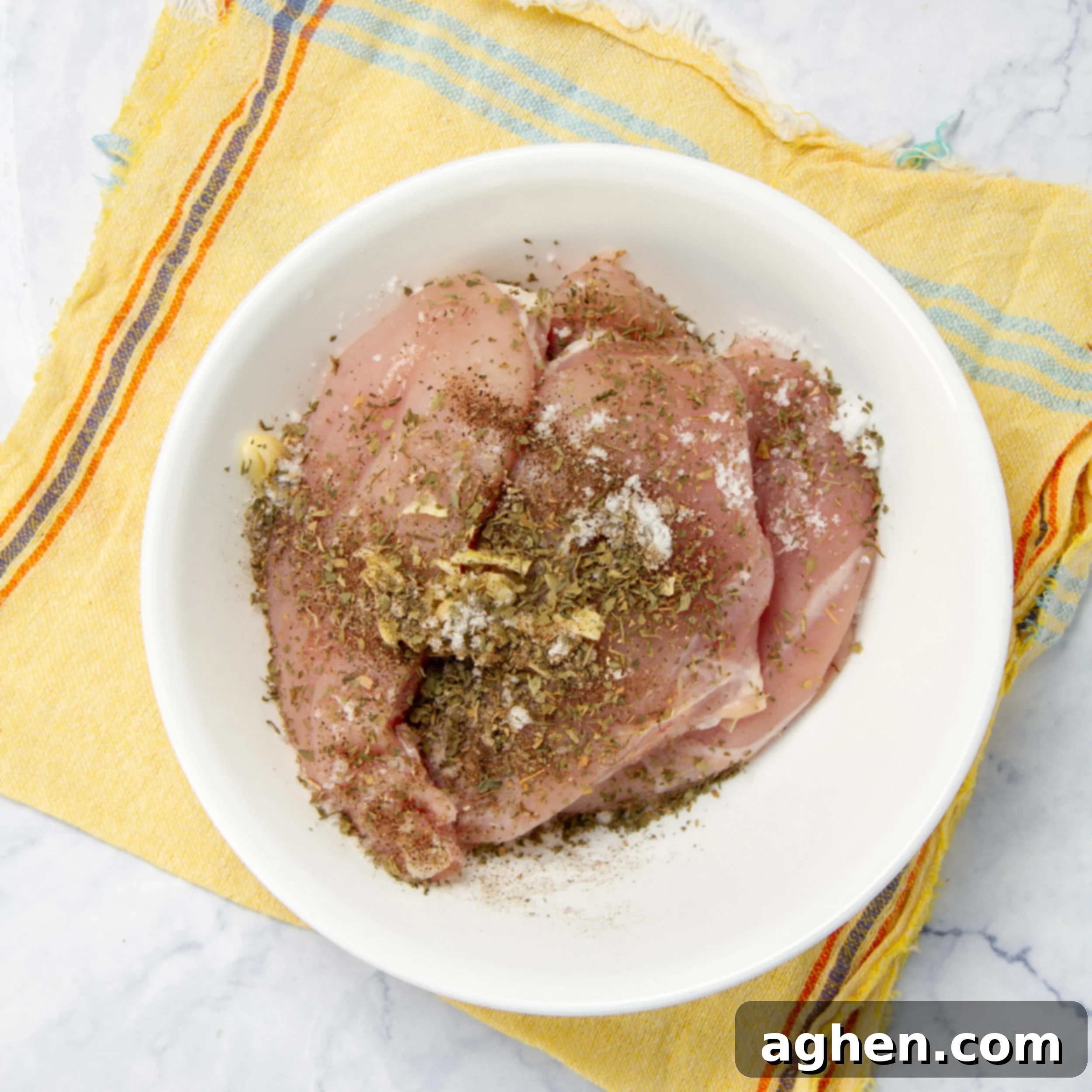 Seasoning the chicken breast with a spice mixture in a small bowl, showing the hands at work.