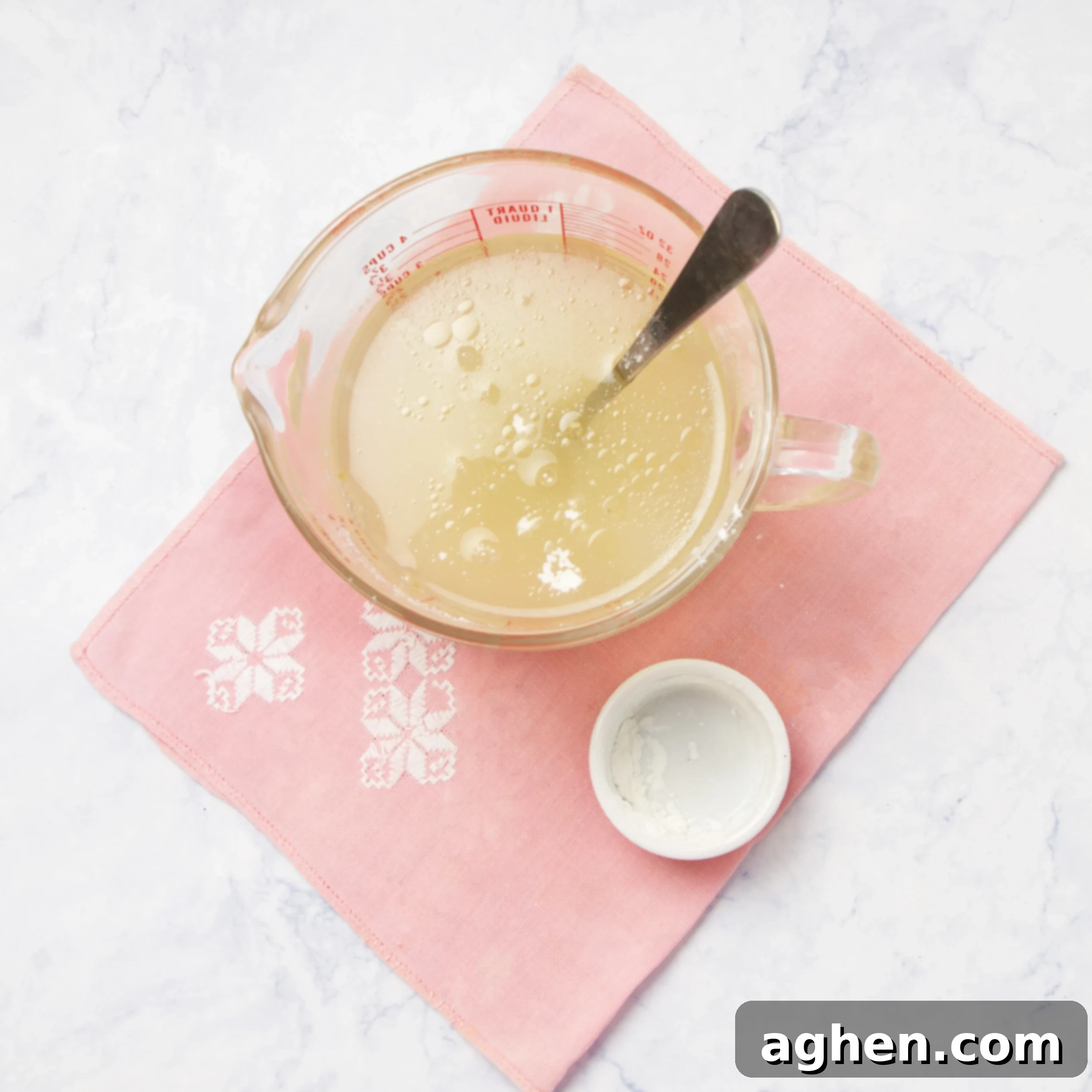 Cornstarch slurry being whisked with chicken broth in a measuring cup, creating the creamy sauce base.