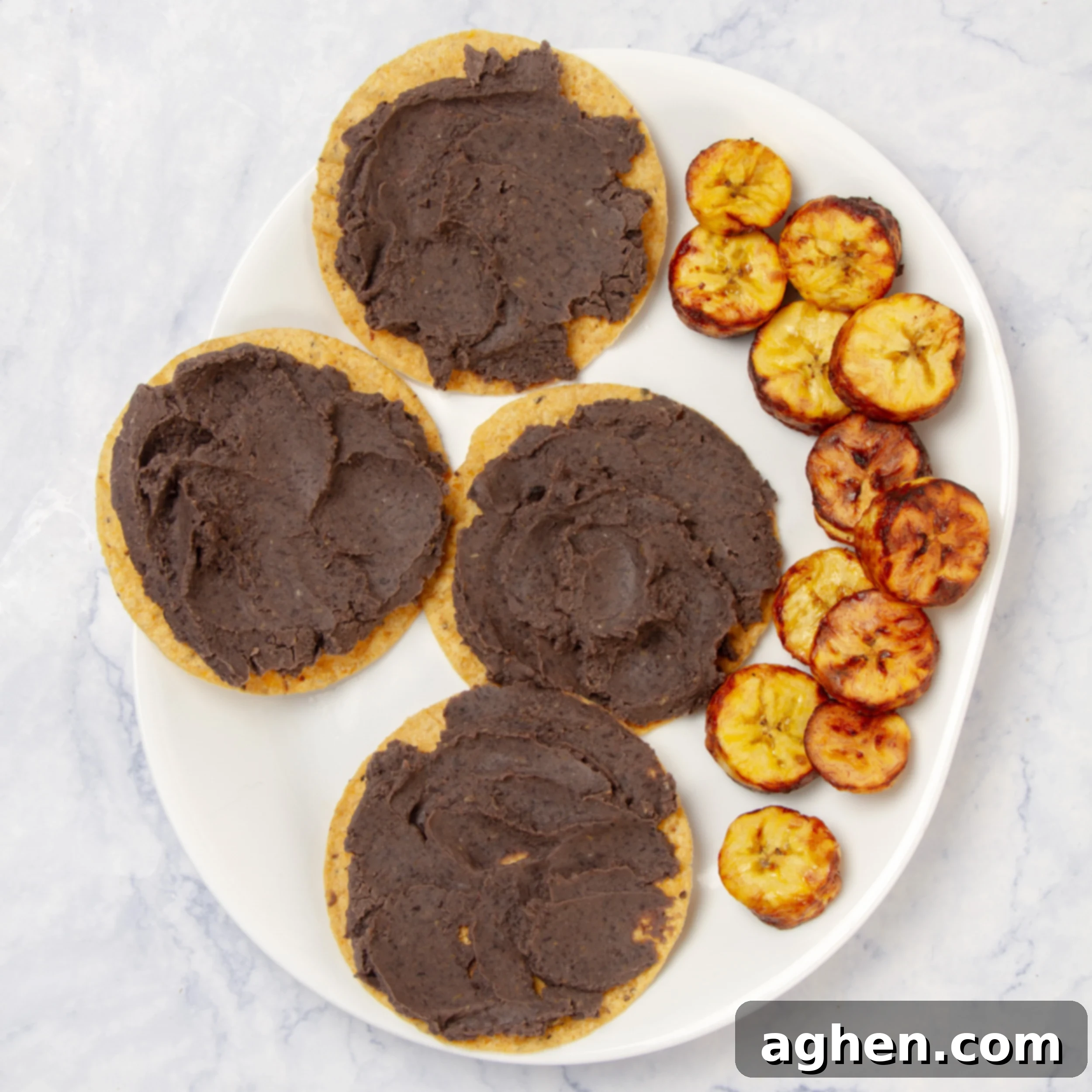 Motul-Style Eggs 5 Four crispy corn tortillas topped with refried black beans, with air-fried plantains on the side.