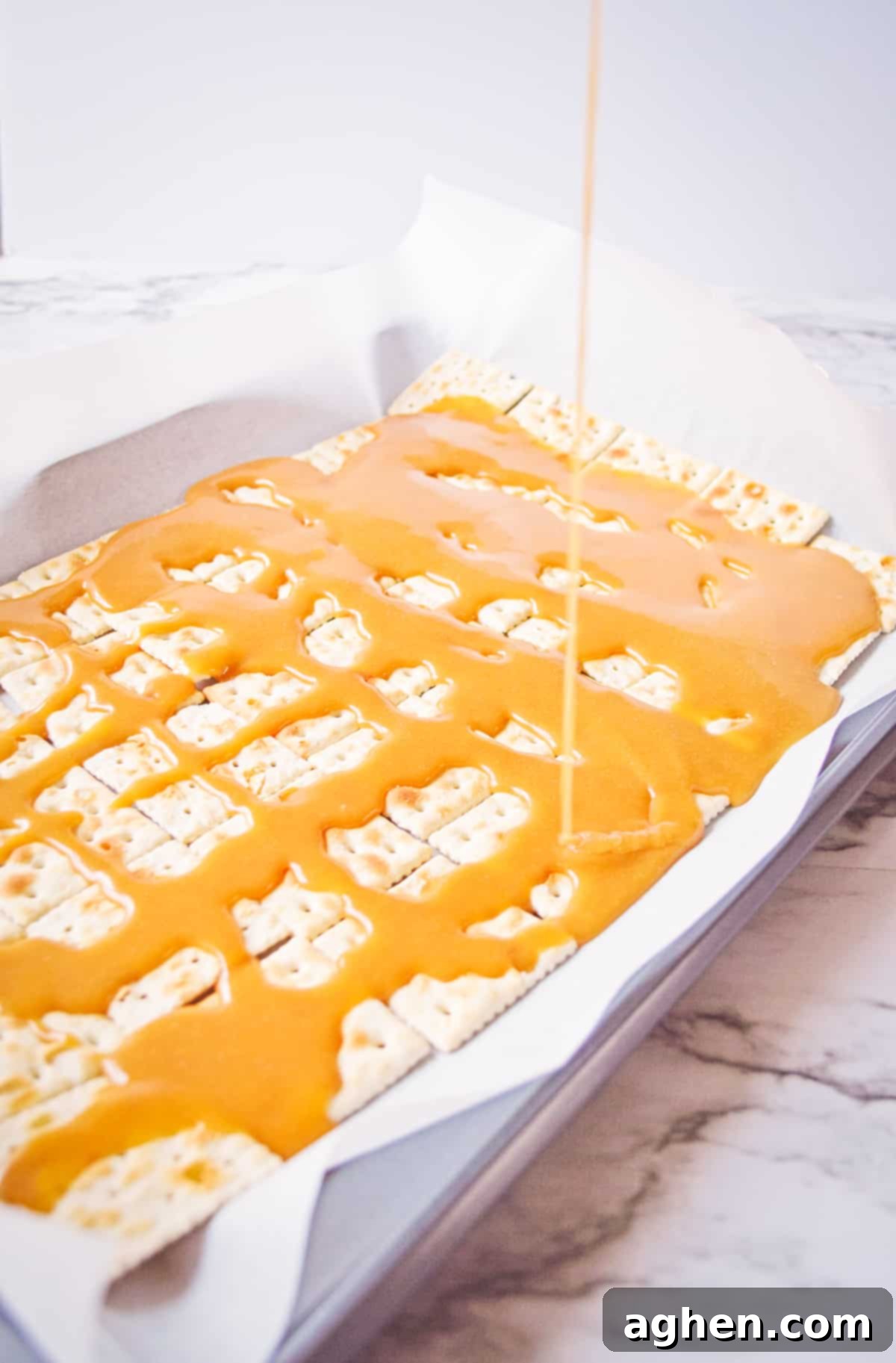 Toffee being poured on saltine crackers.