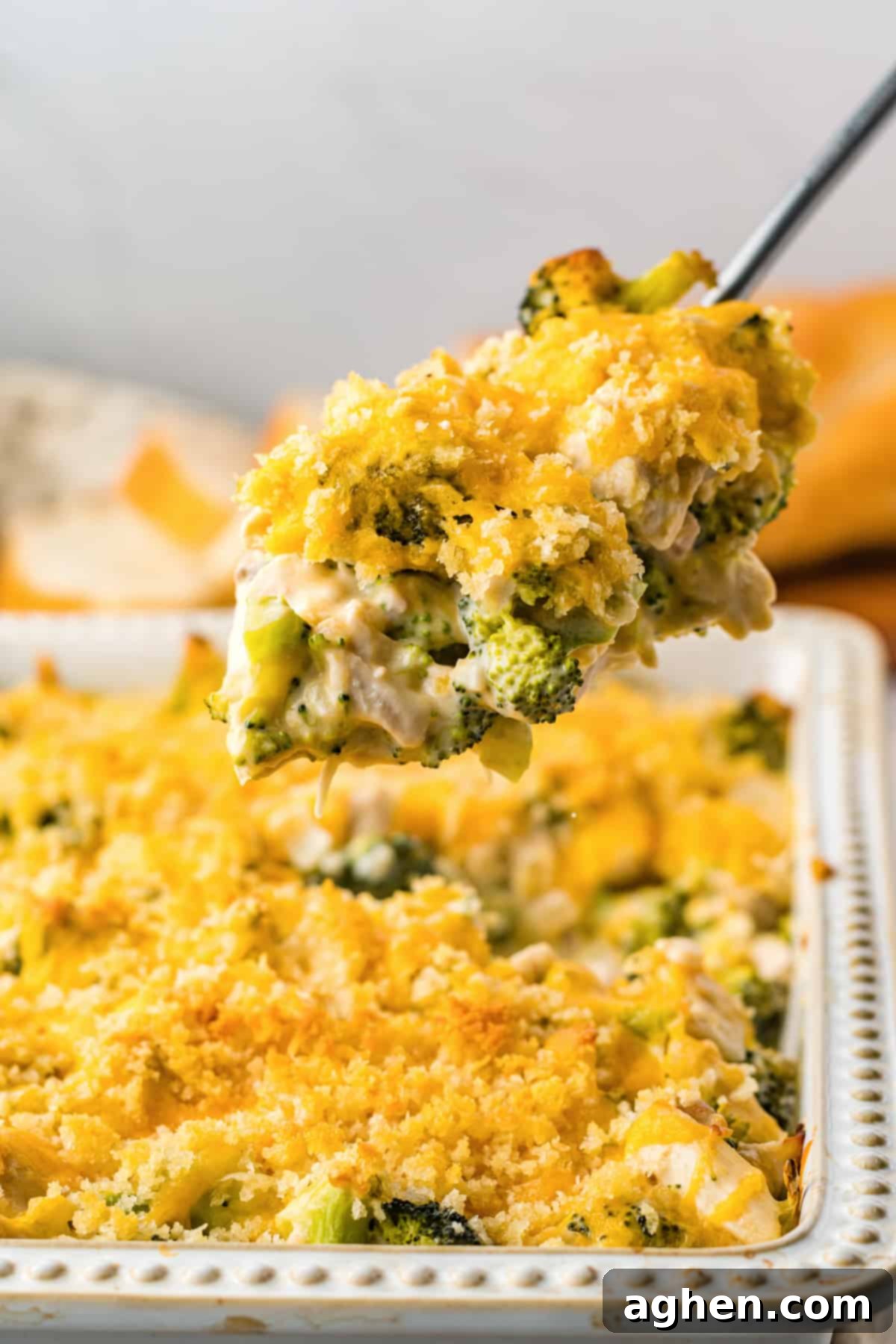 Serving spoon lifting a serving of chicken divan out of casserole dish.